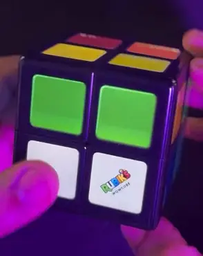 WOWCube lit up green and white in a dark room